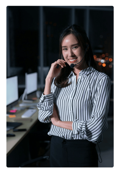 Woman standing in front of some computers with a headset on, wearing a stripped shirt and wearing a headset. Woman standing in front of some computers with a headset on, wearing a stripped shirt and wearing a headset.