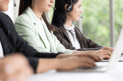 People working on computers with headsets on to answer customer calls.