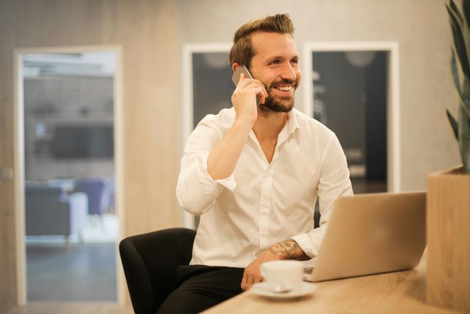 Smiling man on the phone in front of a laptop