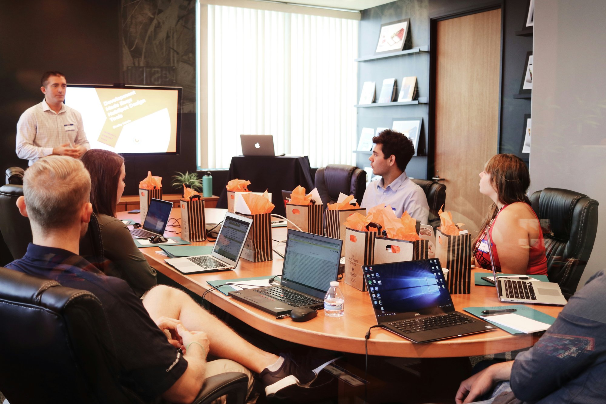 Group of businesspeople sitting in a meeting discussing sales data.