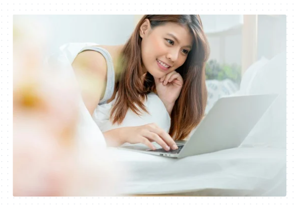 Woman sitting on couch shopping on her laptop.
