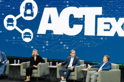 A sweeping cinematic wideangle photograph inside a massive convention center expo floor Dozens of sleek futuristic electric semitrucks and autonomous-1