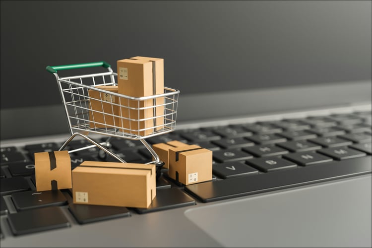 small shopping cart with packages sitting on top of a laptop keyboard