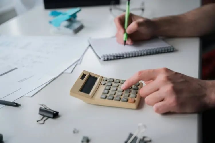 Person doing accounting with a pencil, paper and calculator