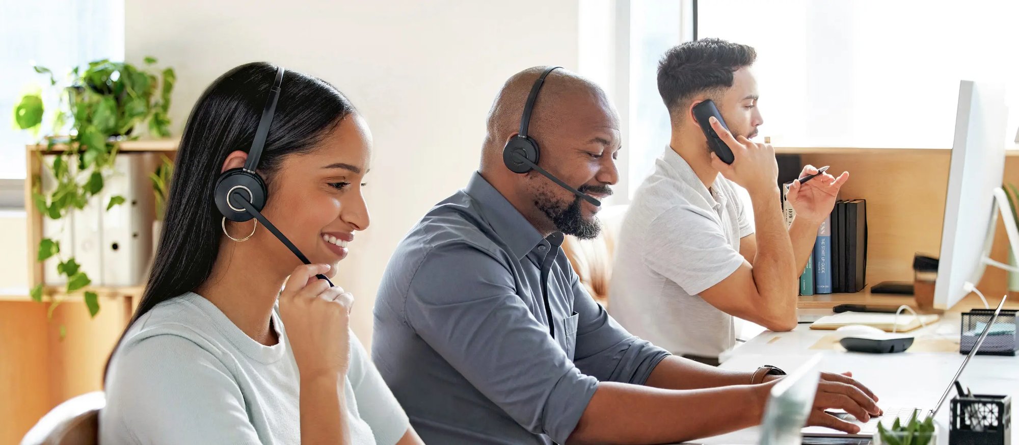Customer Support Personnel working on computers with headsets on.  