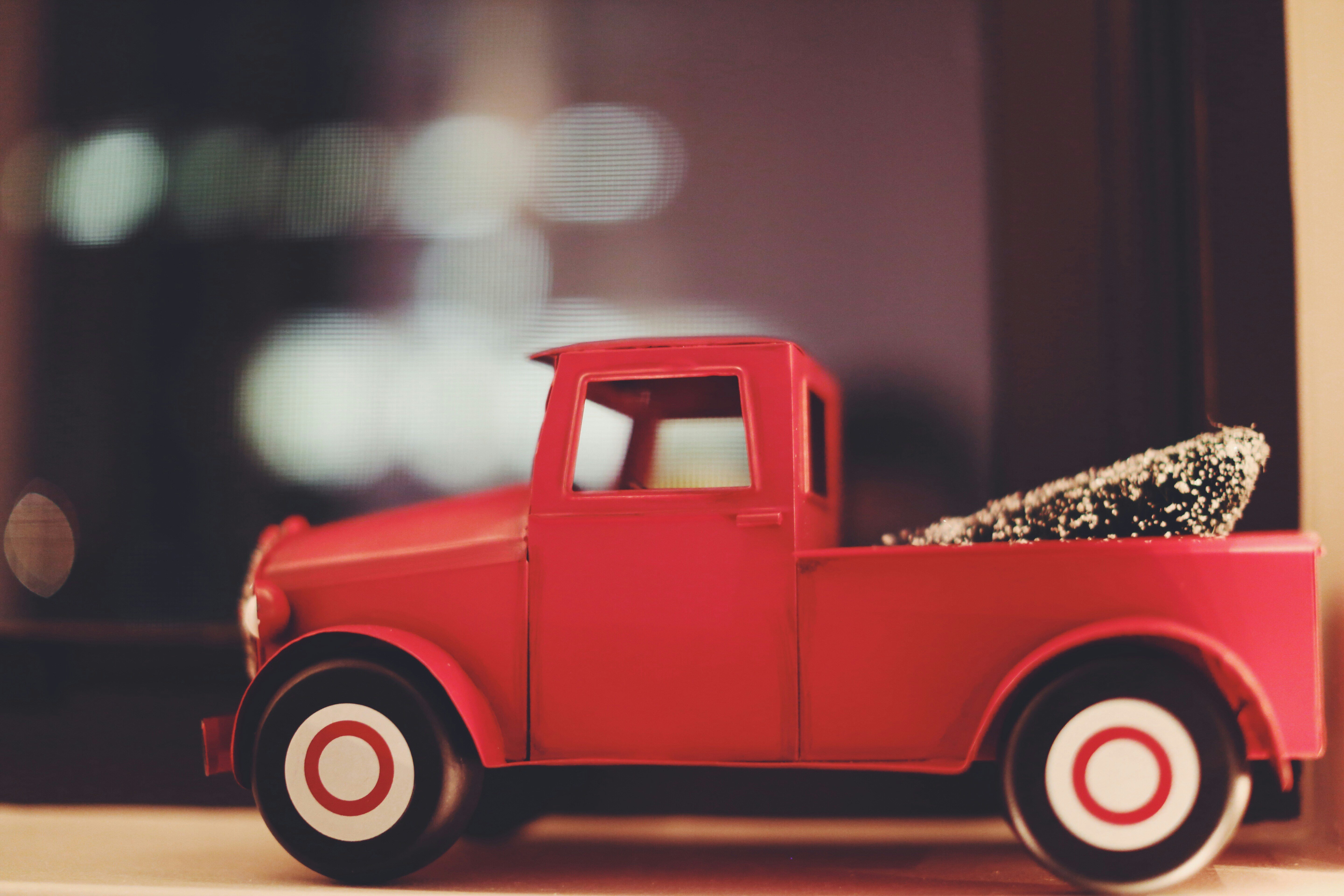 Red toy pickup truck with a Christmas tree in the bed.  