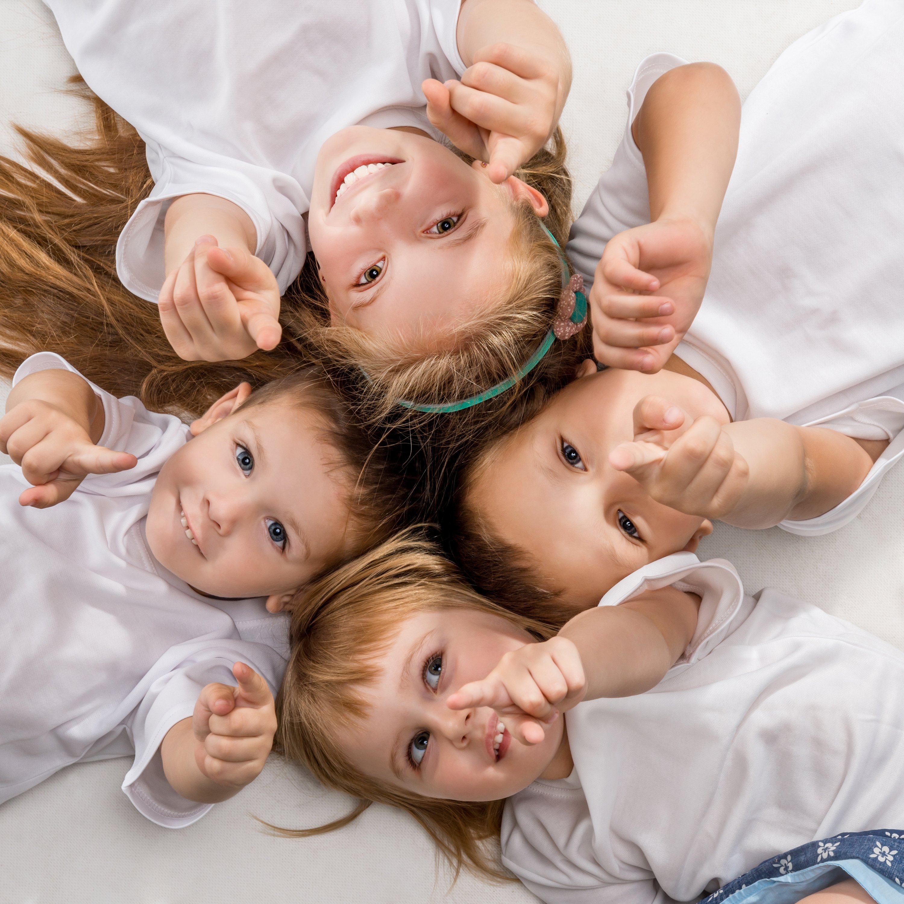 smiling-children-lying-with-their-heads-together-2025-03-31-11-20-49-utc